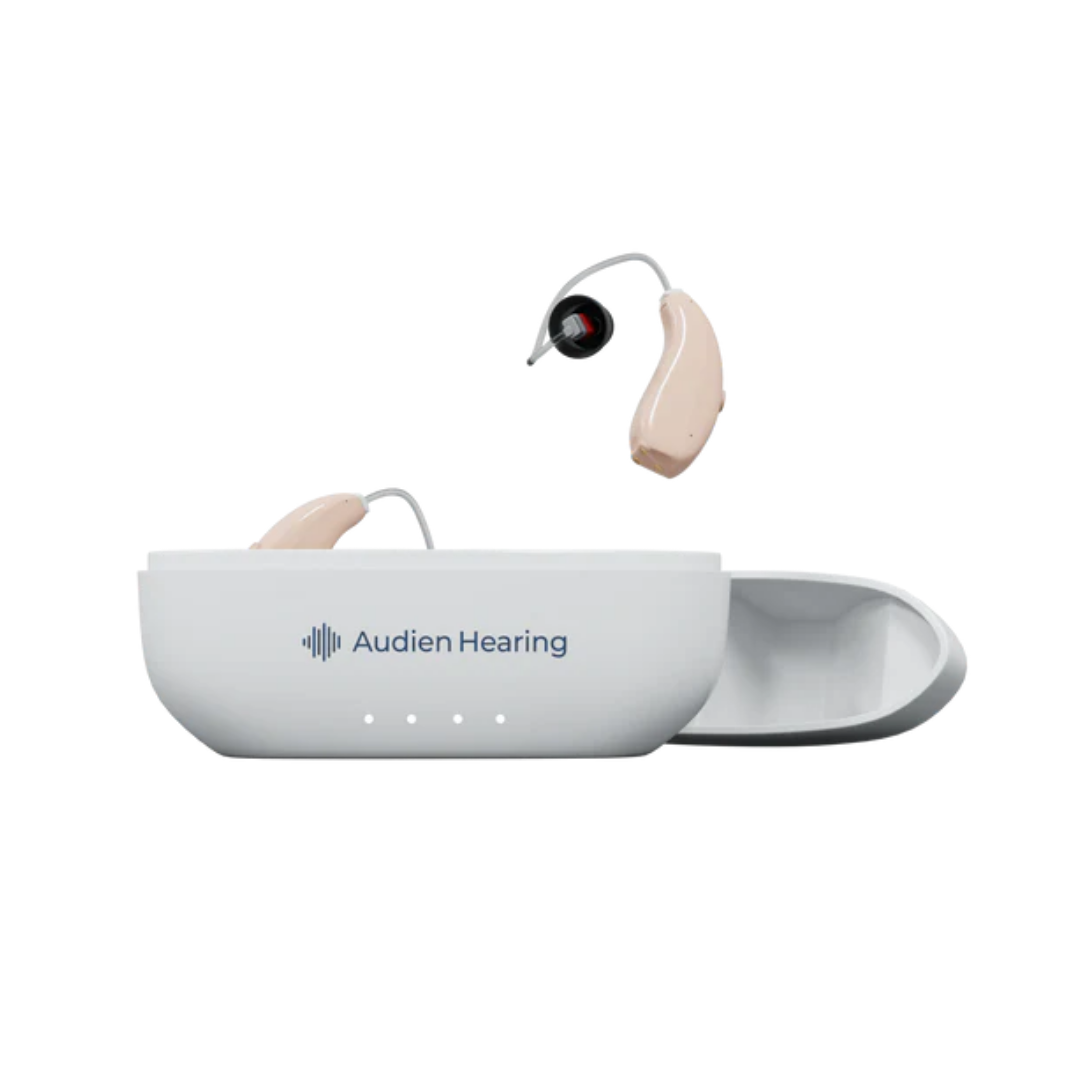 A pair of Audien Hearing ION Pro Over-The-Ear High Def beige hearing aids with thin wires are shown—one in an open white charging case, the other floating above—both featuring personalized hearing profiles for tailored listening.