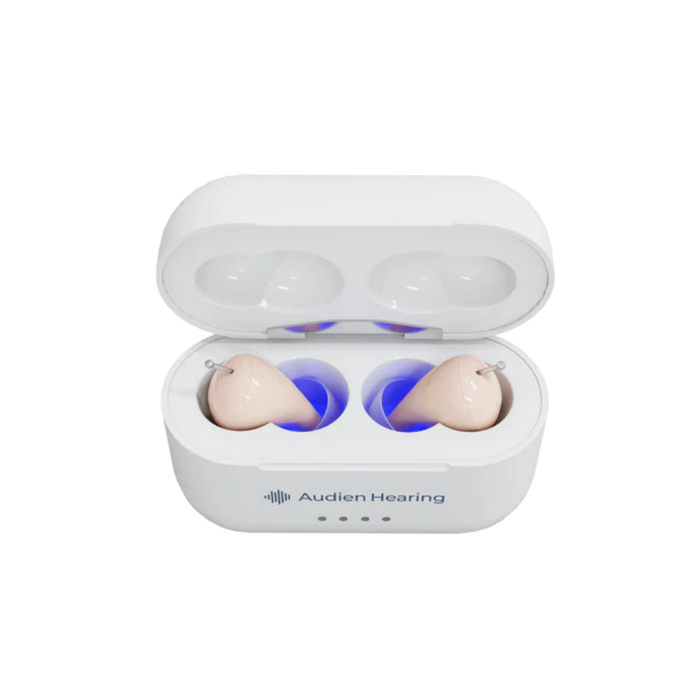 A white Audien Hearing Atom Pro 2 In-Ear OTC Hearing Aids case with the lid open displays two beige hearing aids lit by blue light. The case has the Audien logo, three front indicator lights, and advanced hearing modes powered by the A2™ chip.