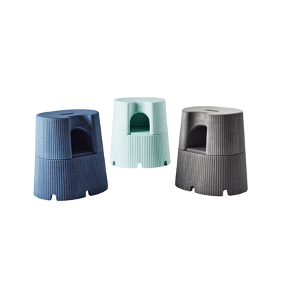 Three small byACRE DORICA Versatile Step Stool & Seats in blue, light green, and gray, featuring ribbed surfaces, built-in handles, and arched side cutouts, are arranged against a plain white background.