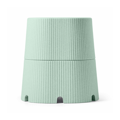 A light green, ribbed, cylindrical container with a tapered design and arch-shaped base openings, inspired by the byACRE DORICA Versatile Step Stool & Seat—water-resistant and anti-slip.