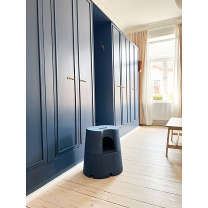 A minimalist room with tall blue built-in wardrobes, light wooden floors, a byACRE DORICA Versatile Step Stool & Seat (Water-Resistant & Anti-Slip), a wooden bench, large windows with beige curtains, and sunlight streaming in.