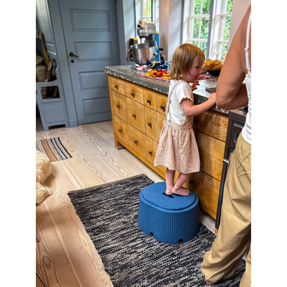 A young child uses the byACRE DORICA Versatile Step Stool & Seat beside an adult at the kitchen counter, reaching for items. The stool is water-resistant and anti-slip, perfect for kitchens with wooden cabinets and natural light.