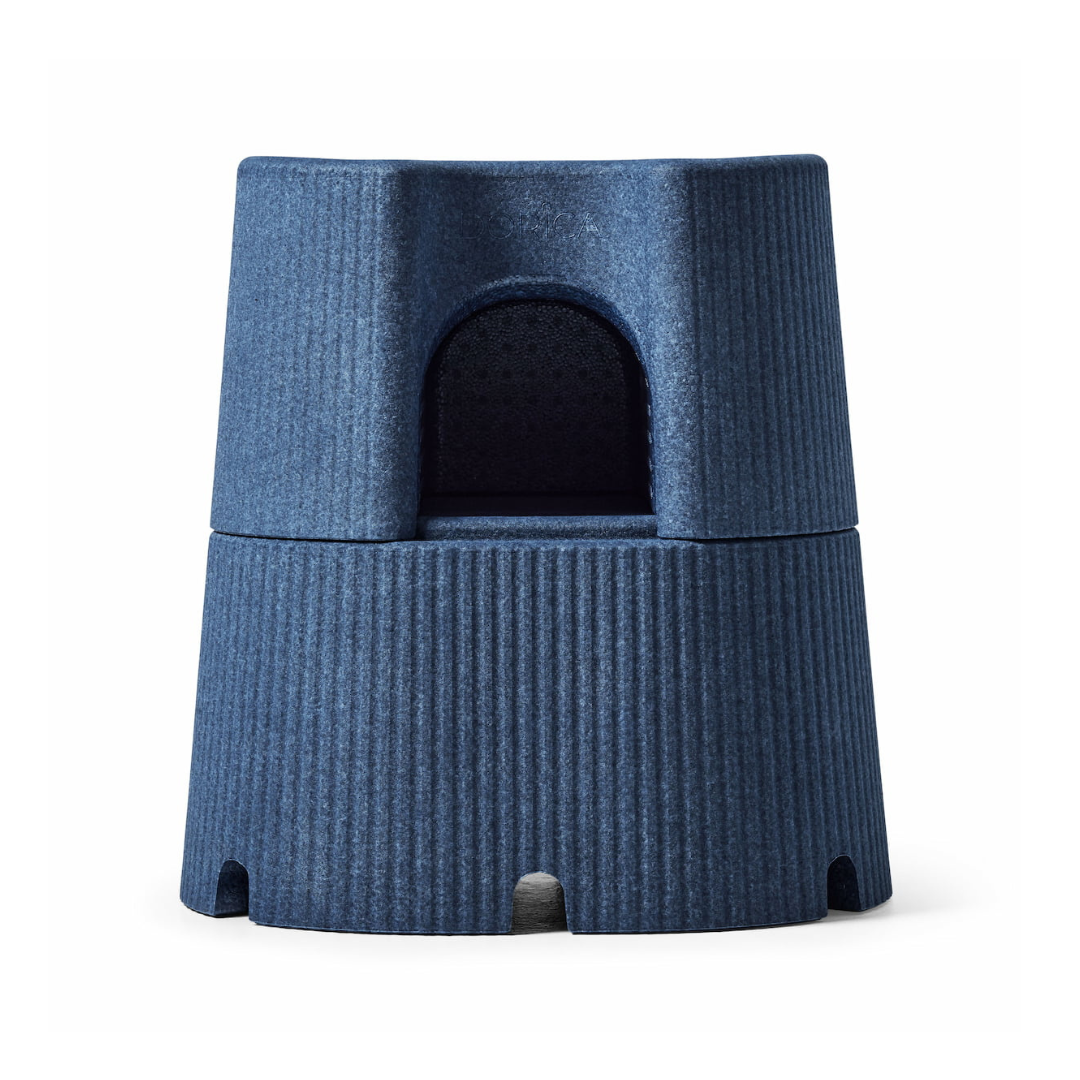 A blue, cylindrical object with a ribbed texture and rounded entrance, featuring small base openings and resembling the water-resistant, anti-slip byACRE DORICA versatile step stool and seat.