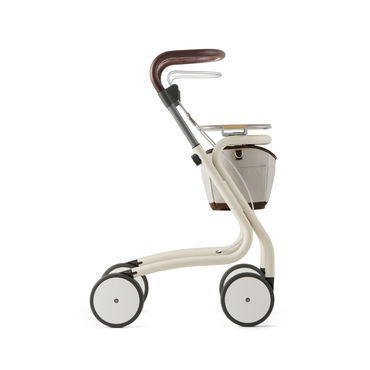 The byACRE Scandinavian Butler At-Home Rollator, shown in profile on a plain white background, features a modern cream design with a brown handle, four white wheels, and a minimalist Scandinavian aesthetic with a small under-seat basket.