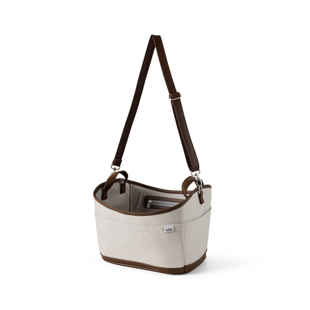 The byACRE Scandinavian Butler At-Home Rollator features a beige canvas design with brown leather trim, a wide adjustable strap, open-top style, and a side exterior pocket, inspired by Scandinavian Butler aesthetics.