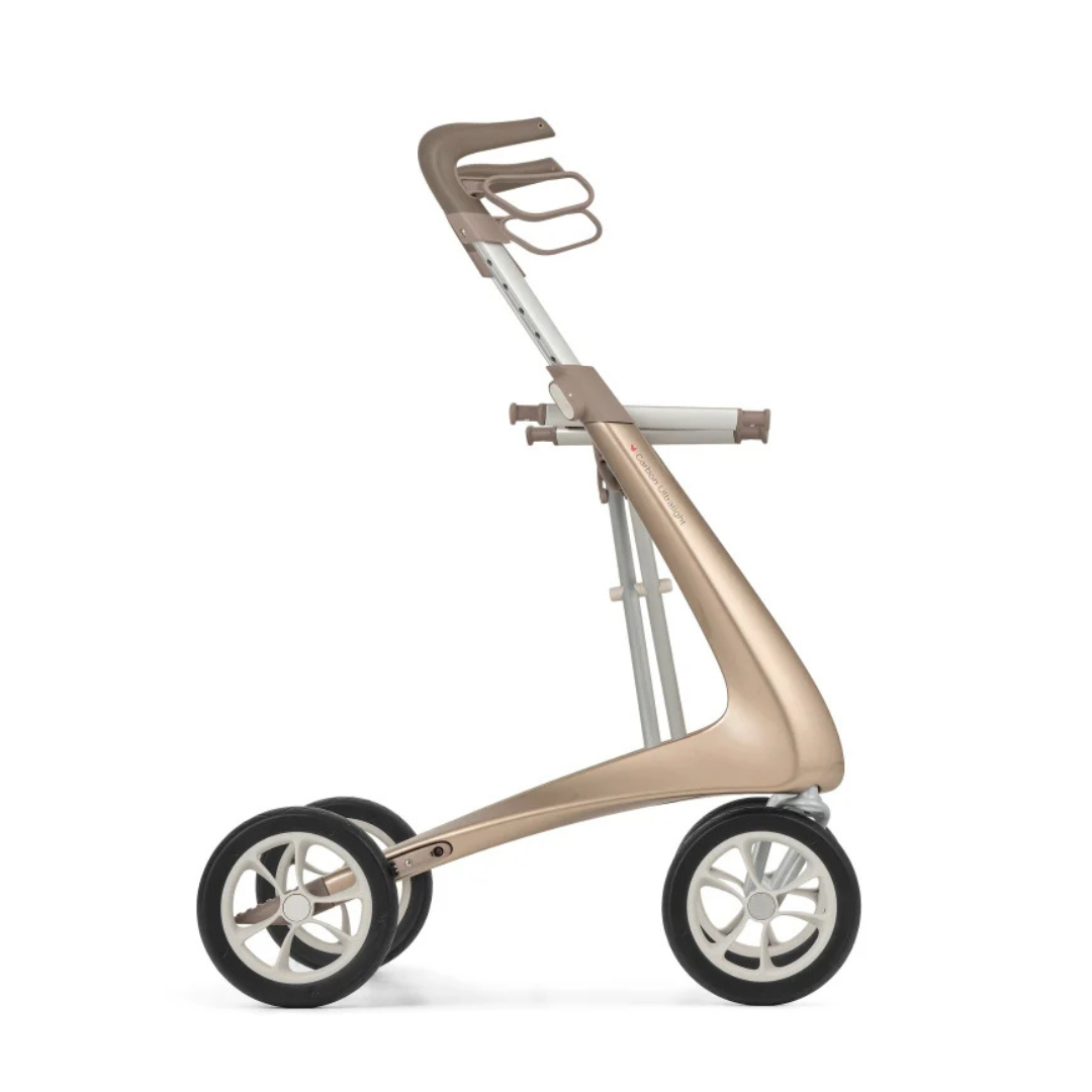 The ByACRE Ultralight Carbon Fiber Rollator is a modern, minimalist frame with three large wheels and a metallic gold finish, shown side view without seat or carriage; weighs just 10.6 lbs.