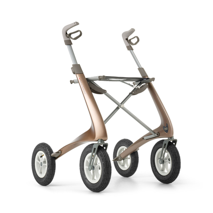 The ByACRE Carbon Overland All-Terrain Rollator features a modern metallic bronze frame, four large black rubber wheels with white hubs, and ergonomic handles—your sleek, lightweight companion for exploring and essential travel.