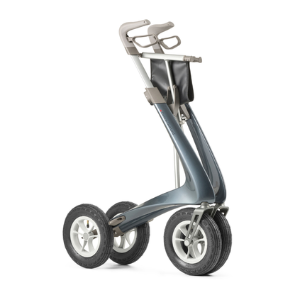 The ByACRE Carbon Overland All-Terrain Rollator pairs a sleek metallic frame, large rubber tires, ergonomic handles, and a black storage pouch—perfect for comfort and confidence on any daily adventure.