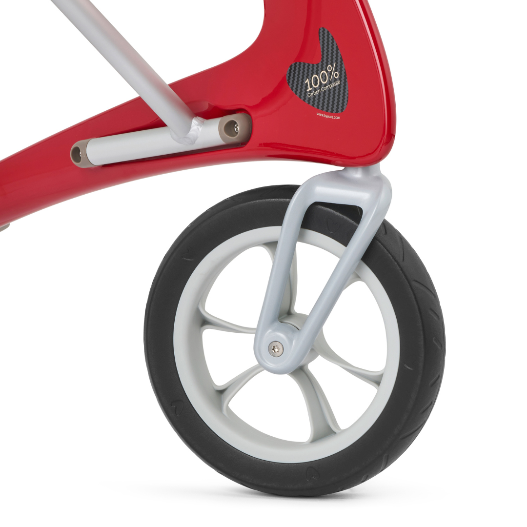Close-up of the front wheel of a red and white balance bike, featuring a black tire with white rim and red frame with 100% logo—evoking the modern, lightweight design of the 10.6 lb ByACRE Ultralight Carbon Fiber Rollator.