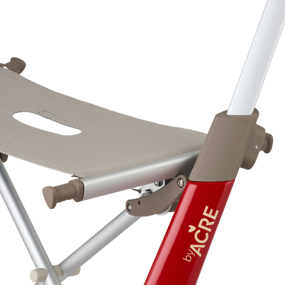 Close-up of a beige fabric seat and part of the red and silver metal frame on the ByACRE Ultralight Carbon Fiber Rollator (10.6 lbs), highlighting the seat and joint details that showcase the sleek design of this mobility aid.