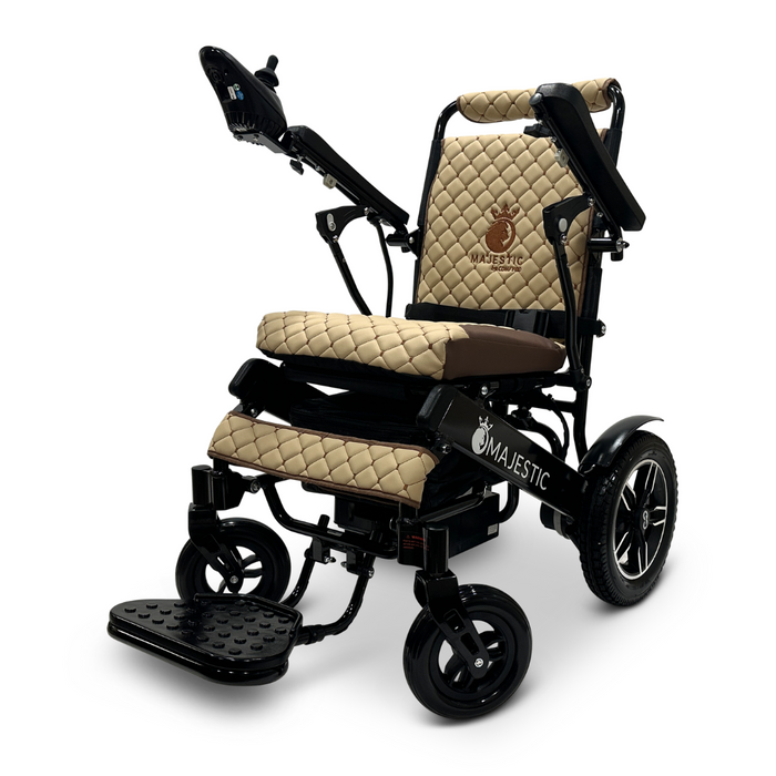 The ComfyGo MAJESTIC IQ-8000 Remote Controlled Lightweight Electric Wheelchair is a sleek, black and beige model that features quilted padding, armrests, and a footrest for comfort. Designed with travel-friendly convenience in mind, it includes a joystick control on the right armrest and sturdy wheels for enhanced mobility. The name "Majestic" is prominently displayed on the backrest and side.