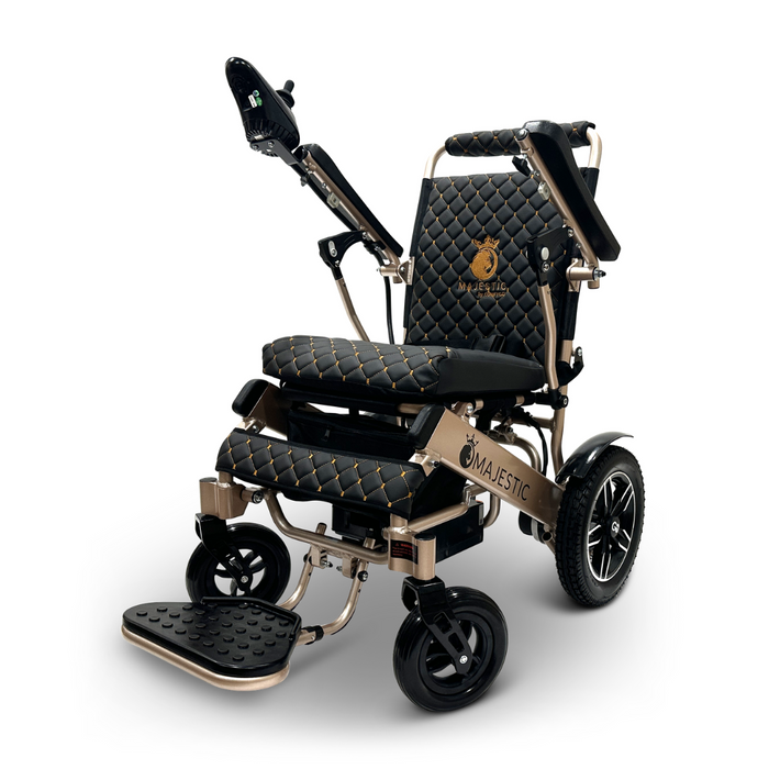 Introducing the ComfyGo MAJESTIC IQ-8000, a luxurious black and gold electric wheelchair with quilted cushioning. It features large rear wheels, foldable armrests, and a joystick controller on the right armrest. This travel-friendly, lightweight model showcases the Majestic brand name gleaming in gold on the backrest.