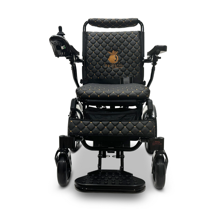 Introducing the ComfyGo MAJESTIC IQ-8000, a luxurious and travel-friendly black electric wheelchair adorned with elegant gold accents. It features quilted upholstery and an embroidered logo on the backrest. The lightweight yet sturdy design includes joystick control and cushioned footrests, exuding sophistication and elegance.