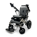 Introducing the ComfyGo MAJESTIC IQ-8000: a stylish and contemporary electric wheelchair featuring a quilted seat and backrest for utmost comfort. Designed to be travel-friendly and lightweight, it includes adjustable armrests, a folding footrest, and large rear wheels for easy maneuverability. The metallic frame proudly displays the Majestic name on the side.