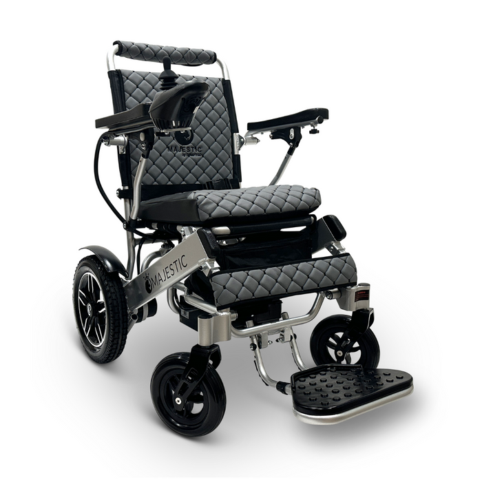 The ComfyGo MAJESTIC IQ-8000 Remote Controlled Lightweight Electric Wheelchair is a black and silver model featuring a quilted seat and backrest design, armrests, a joystick for navigation, and a footrest. This travel-friendly wheelchair is lightweight and positioned facing slightly to the left for easy maneuvering.