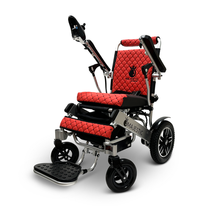 The ComfyGo MAJESTIC IQ-8000 Remote Controlled Lightweight Electric Wheelchair is a portable, electric wheelchair available in red and black. It boasts quilted upholstery and elevated armrests for added comfort. The design includes large rear wheels, smaller front wheels, a footrest, and a lightweight frame. The brand's logo is prominently displayed on the backrest and side panels.