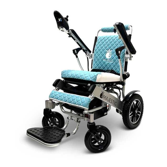 Introducing the ComfyGo MAJESTIC IQ-8000, a lightweight, travel-friendly electric wheelchair in an elegant light blue and white design. This model comes with quilted cushions, comfortable armrests, and a collapsible footrest. With large rear wheels and smaller front ones for optimal maneuverability, the Majestic brand logo is prominently displayed on the frame.