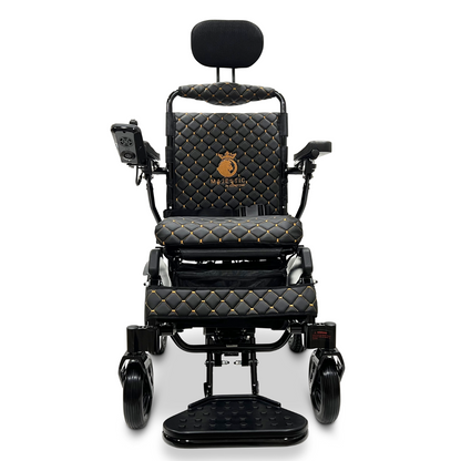 The ComfyGo MAJESTIC IQ-9000 Auto Recline Remote Controlled Electric Wheelchair showcases a sleek black electric design with luxurious quilted upholstery and elegant gold accents. It includes a digital joystick controller on the right armrest, a raised footrest that reveals small front wheels, and is powered by brushless silent motors for smooth and serene mobility.