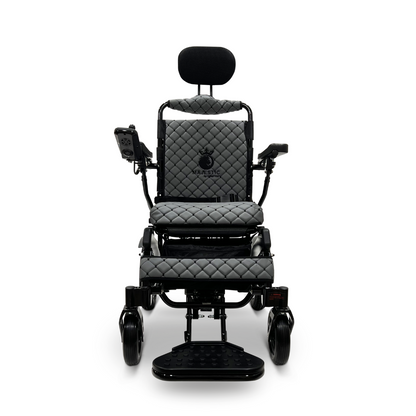 The ComfyGo MAJESTIC IQ-9000 Auto Recline Remote Controlled Electric Wheelchair showcases a sophisticated black and grey design, complete with quilted padding on the seat, backrest, and armrests. It includes a digital joystick controller situated on the right armrest, along with a headrest and footrests, all powered by brushless silent motors for an effortlessly smooth ride.