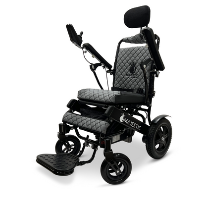 The ComfyGo MAJESTIC IQ-9000 Auto Recline Remote Controlled Electric Wheelchair, featuring a refined quilted design in sleek black, offers a padded headrest and adjustable armrests for added comfort. Its brushless silent motors combined with a digital joystick controller provide seamless operation. With large rear wheels and smaller front ones for improved maneuverability, the Majestic branding is prominently displayed on the side.
