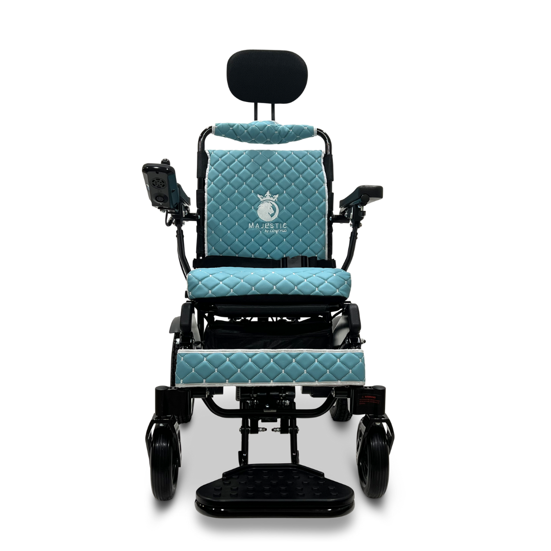 Introducing the ComfyGo MAJESTIC IQ-9000 Auto Recline Remote Controlled Electric Wheelchair in a vibrant blue color, complete with a luxurious quilted seat and backrest. It features brushless silent motors for a smooth ride and includes a digital joystick controller conveniently located on the right armrest. The elegant word 'Majestic,' accompanied by a crown logo, is finely embroidered on the backrest.
