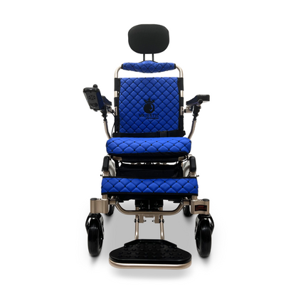 The ComfyGo MAJESTIC IQ-9000 Auto Recline Remote Controlled Electric Wheelchair showcases an elegant blue design with quilted upholstery on the seat and backrest, complete with a headrest. The digital joystick controller located on the armrest, combined with brushless silent motors, ensures smooth navigation when observed from the front view.