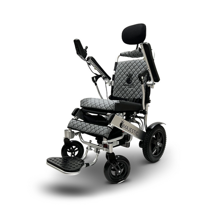 The ComfyGo MAJESTIC IQ-9000 electric wheelchair combines black and silver hues with a quilted seat, backrest, headrest, armrests, footrest, and right-mounted digital joystick controller. Its Majestic branding adorns the front and features automatic reclining for enhanced comfort.