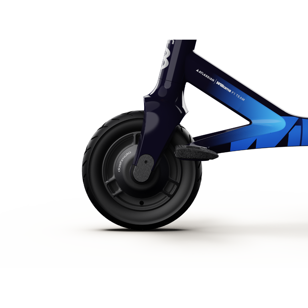 Close-up of a black front wheel on the dashmoto® dash 3 Williams Carbon Fiber Scooter, featuring a dark blue frame and blue graphic accents, with part of the fork and motor housing visible. See background info for specs and warranty details.