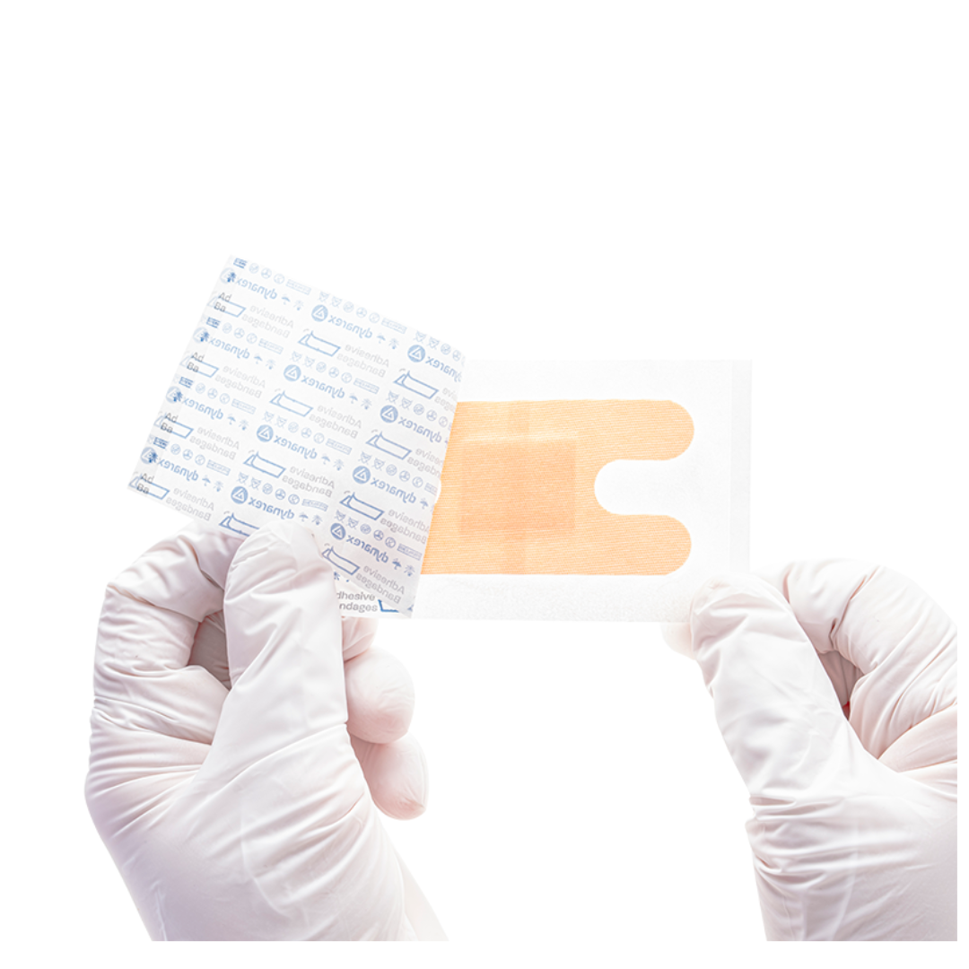 Gloved hands hold a transparent Dynarex DynaSafety Adhesive Fabric Bandage with an orange pad, partially peeled from its paper backing, against a white background.