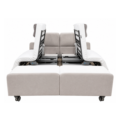 The Elevra Deluxe Rotating Lift Assist Bed - Dual King features a modern beige and white design with adjustable backrests and footrests, visible frame and reclining mechanisms inspired by homecare beds, and smooth wheels for easy movement.