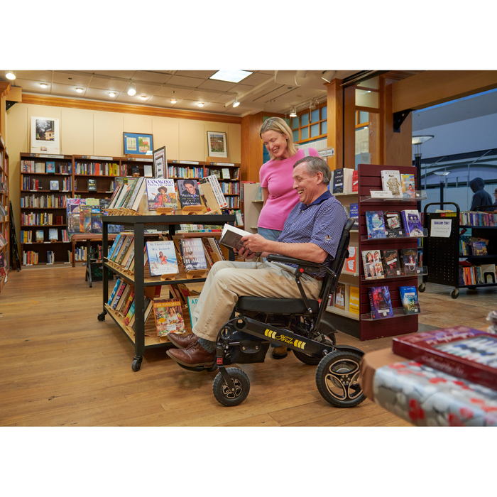 Man and woman at the library using the Golden Tech Stride Folding Lightweight Powerchair