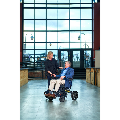 Man and woman at the airport using the Golden Tech Stride Folding Lightweight Powerchair