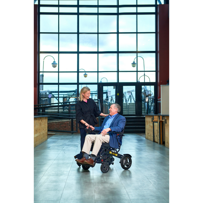 Man and woman at the airport using the Golden Tech Stride Folding Lightweight Powerchair