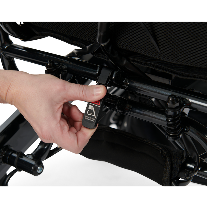 A close-up of a hand adjusting a lever on the Golden Tech Stride Folding Lightweight Powerchairs black metal frame, highlighting joystick maneuverability amid its metal bars and springs.
