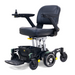 The Golden Tech GP130 Buzzaround CarryOn is an ultra-compact, motorized wheelchair with a cushioned seat, armrests, right-arm joystick control, center-wheel drive, foldable footrest, and a small storage basket beneath the seat.