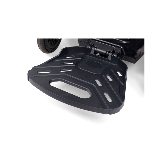 Close-up of the ultra-compact, foldable footplate on the Golden Tech GP130 Buzzaround CarryOn Portable Powerchair. The black footplate has a textured surface, slots, and a handle cutout for easy folding, complementing the scooters 4-wheel suspension for enhanced stability.