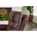 A close-up of the Golden Tech PR446 DeLuna™ Dione Recliner with Lift Assist - Medium in dark brown leather sits in a modern living room. The plush, tufted backrest exudes comfort, while a fireplace and large potted plant add warmth to the space.