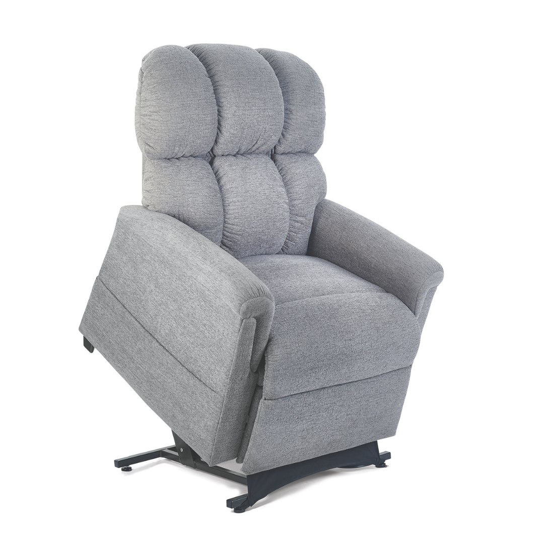 The Golden Tech PR531 Comforter Recliner w/ Lift Assist is a light gray, plush-upholstered power lift chair with a high back and padded armrests, set on a black metal base that tilts forward to help users stand up.