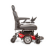 The Golden Tech GP620 Compass HD Bariatric Electric Wheelchair is a red and black heavy-duty power chair with a padded seat, headrest, and armrests. It features center-wheel drive for sleek maneuverability, joystick control on the right armrest, four sturdy wheels, and a robust metal footrest.