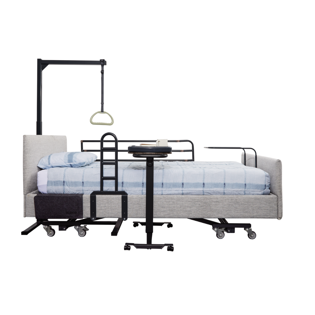 The icare Medical Freestanding Pull-Up Bar supports optimal bed mobility and patient transfers. Shown with side rails, an overbed table, a trapeze bar, assistive transfer poles, and light blue bedding on a modern hospital bed against a white background.
