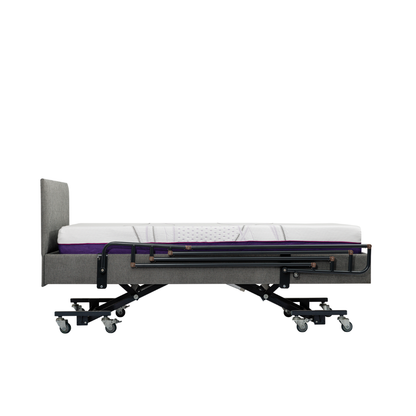 A gray adjustable hospital bed features iCare Medical Bed Safety Rails for support and fall prevention, with a headboard, caster wheels, and a white and purple mattress in flat position. The background is plain white.