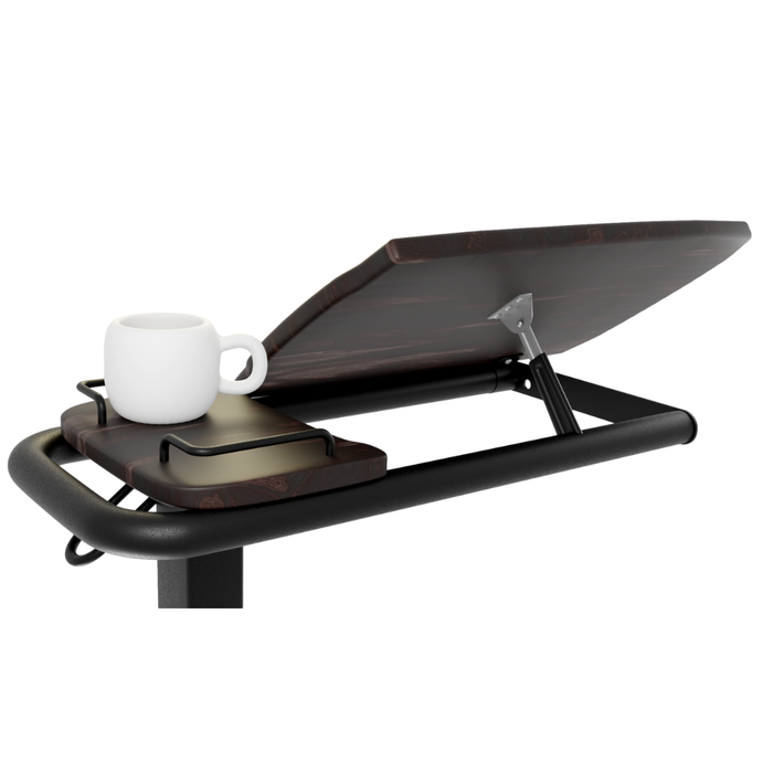 The iCare Medical Over Bed Tilting Table is height adjustable with a dark wooden surface that tilts for multipurpose use. Its flat side holds items like a white coffee mug and closed laptop, while a sleek black metal frame provides support.