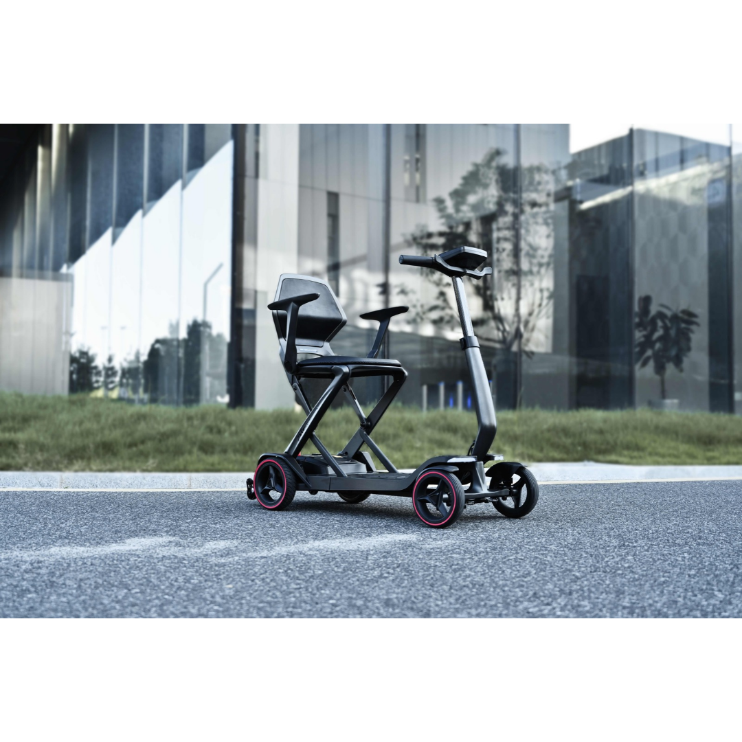An iMOVE AirCarbon Folding Carbon Fiber Scooter with a seat, handlebars, and four wheels with red accents parked on a paved path.