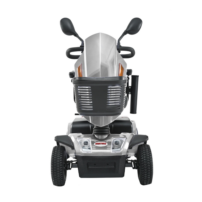 Front view of the Metro Mobility S500 Heavy Duty 4-Wheel Power Scooter in silver with black accents, featuring large wheels, side mirrors, a headlight, and an emblem reading Metro above the footrest. The design is sleek and sturdy.
