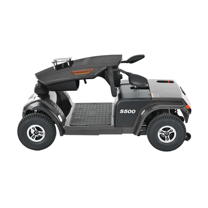 Side view of a Metro Mobility S500 Heavy Duty 4-Wheel Power Scooter in black and gray with a sleek design. It features large wheels, rearview mirrors, a roof with a small windshield, and an interior with textured flooring and a compact dashboard for style and durability.
