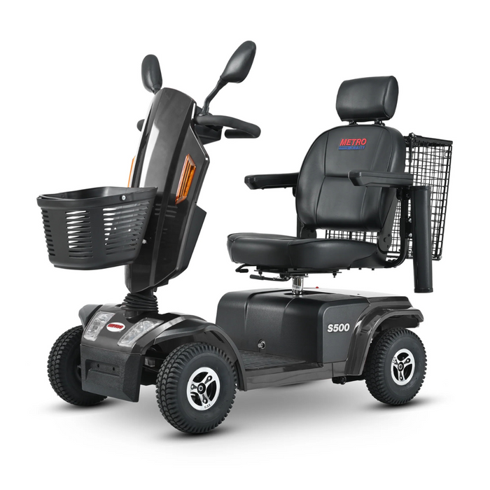 The Metro Mobility S500 Heavy Duty 4-Wheel Power Scooter features a black design with a comfy seat, armrests, backrest, and headrest. It includes front/rear wheels, a front basket, and rear wire carrier. The S500 model name and Metro logo are prominently displayed.