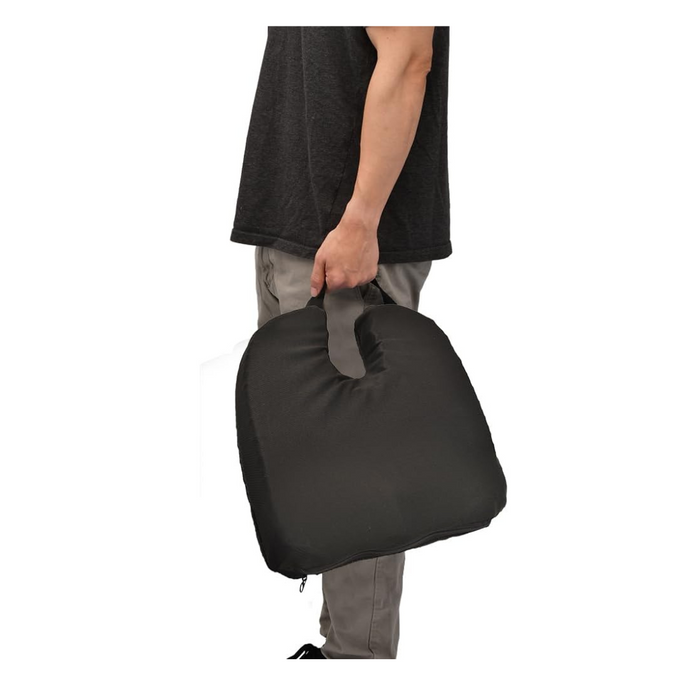A person in a black shirt and gray pants holds a Nova Medical Happy Collection Back and Lumbar Support Gel Cushion with a handle against a plain white background.