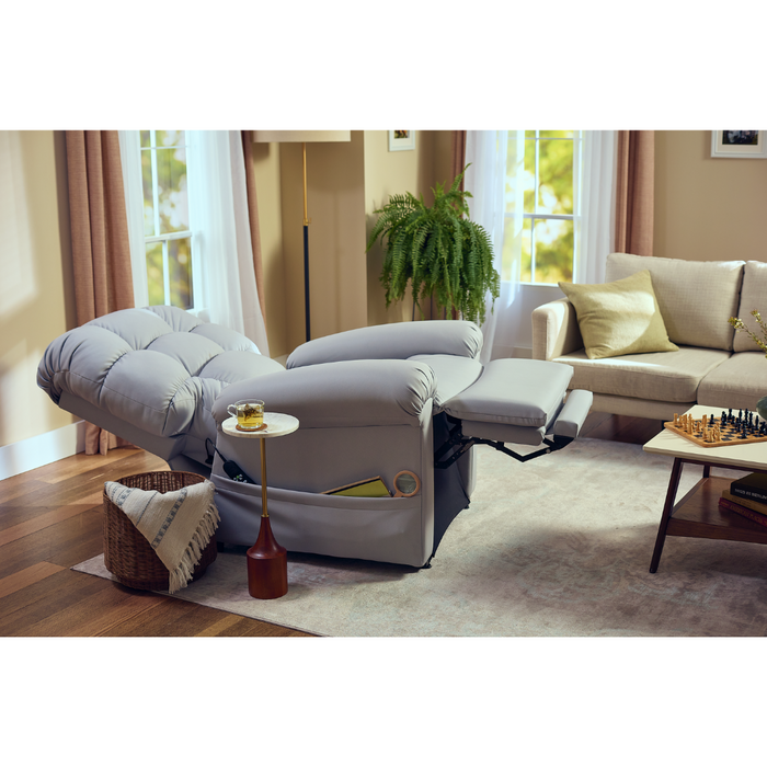 The Journey Perfect Sleep Recliner & Lift Chair with Heat sits elegantly in a cozy living room by a large window. A nearby table holds a drink and lamp, while a beige sofa, green plant, and chessboard in the background enhance the relaxed atmosphere with its therapeutic heat and massage features.