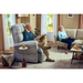 An elderly man relaxes in a Journey Perfect Sleep Recliner & Lift Chair with Heat, reading a book, while an elderly woman is on the sofa with her tablet. Nearby, a chessboard is ready for play. The warmly decorated room with large windows and soft lighting offers a perfect setting for therapeutic heat and massage.