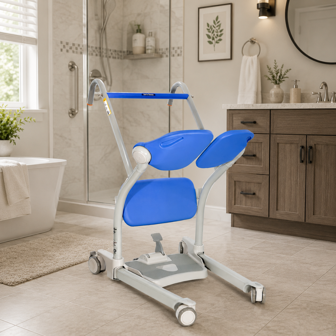 A blue and white ARJO Sara Stedy Manual Standing Aid & Sit-To-Stand Transfer Lift with wheels is in a modern bathroom, near a tub and wooden vanity. It features padded seat and backrest to assist those with limited mobility.